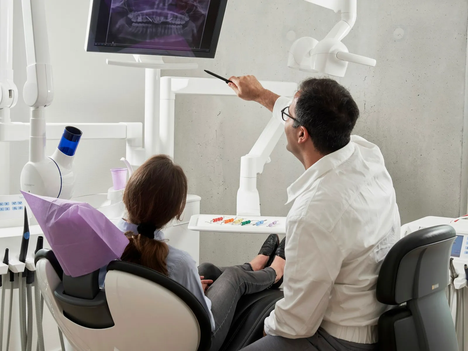 Un dentiste montre une radiographie panoramique à sa patiente dans un cabinet moderne