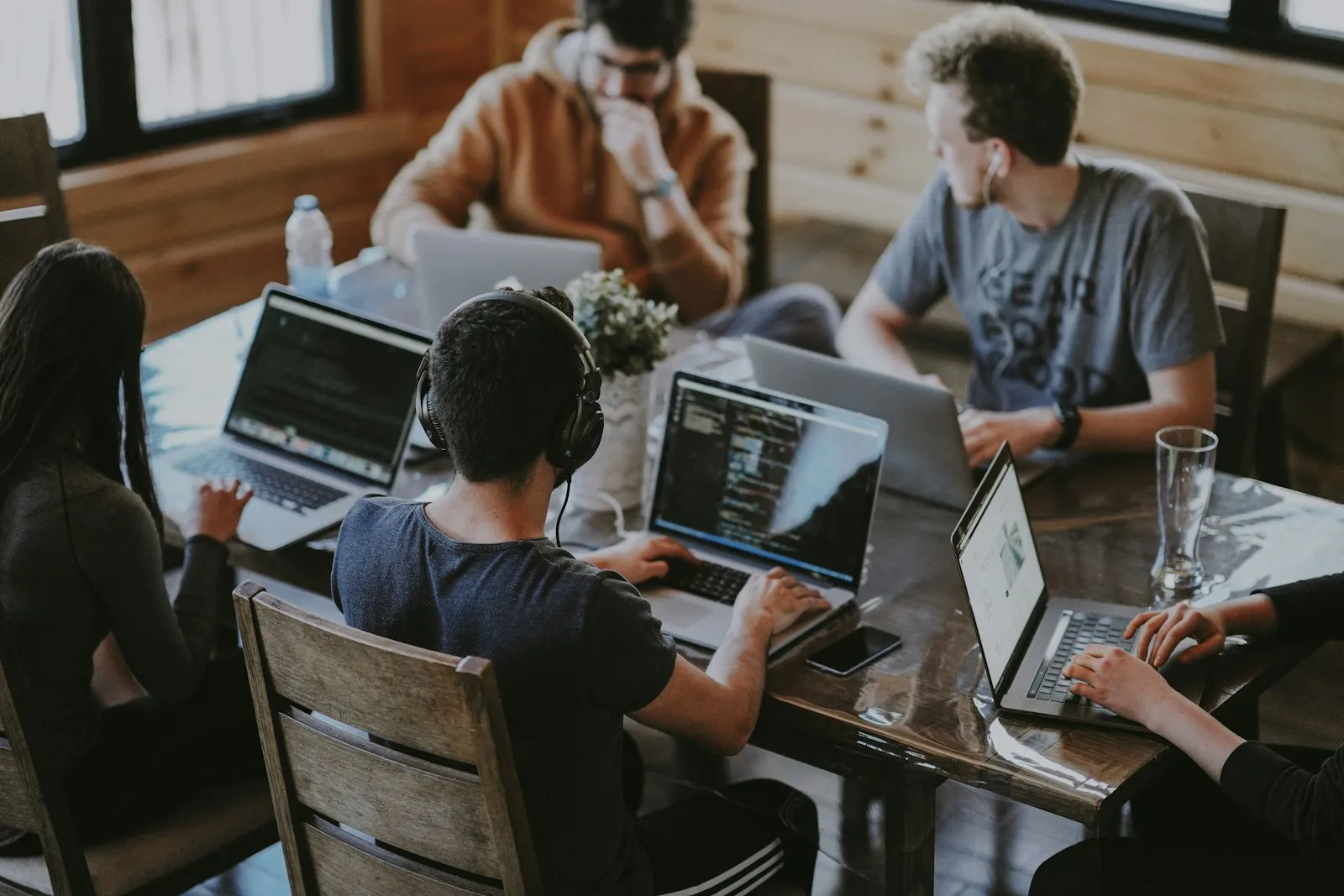 Une équipe concentrée travaille ensemble autour d’une grande table, ordinateurs ouverts