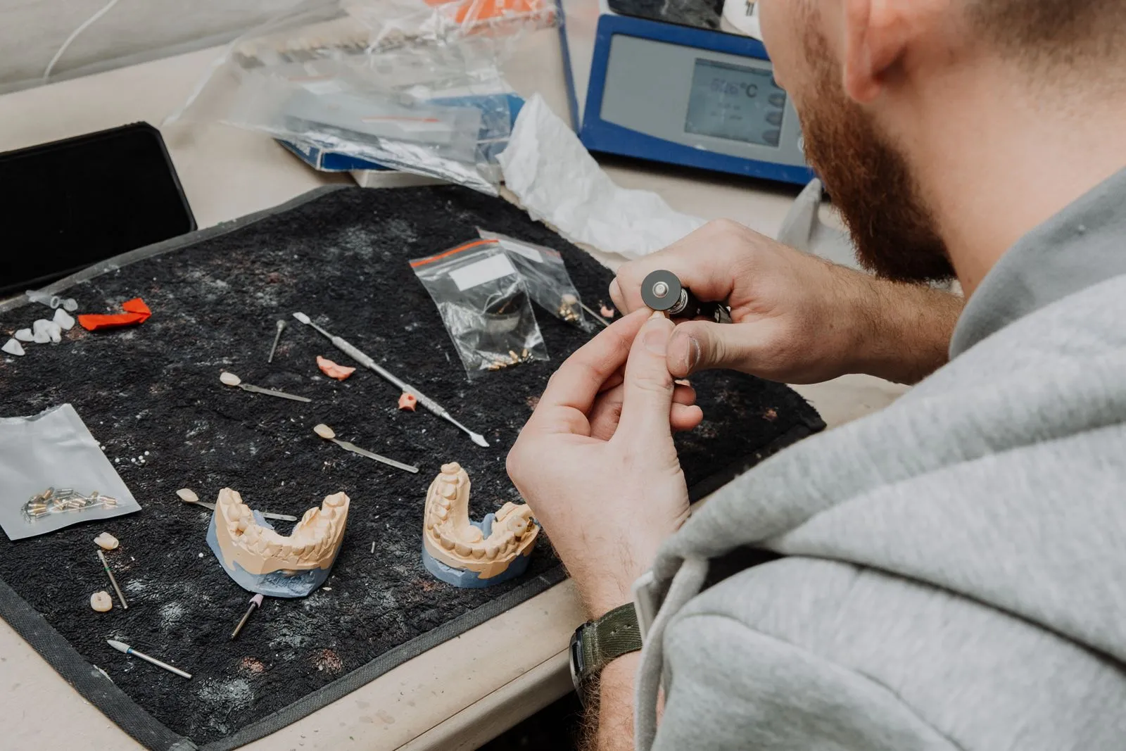 Un prothésiste dentaire travaille sur des moulages de dentiers à son établi de laboratoire